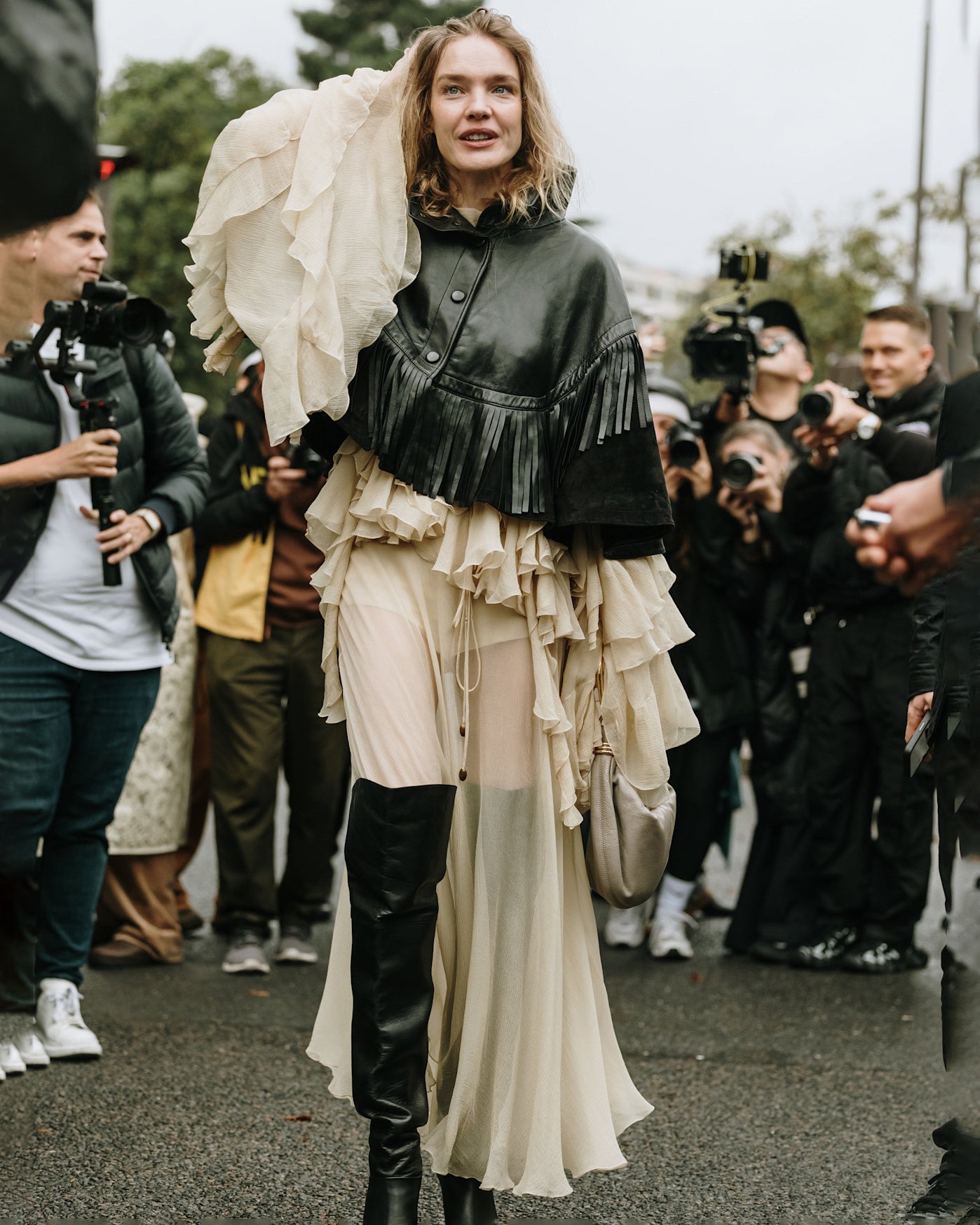 Woman in Paris wearing knee high black leather boots with a billowy dress and cropped black leather jacket.