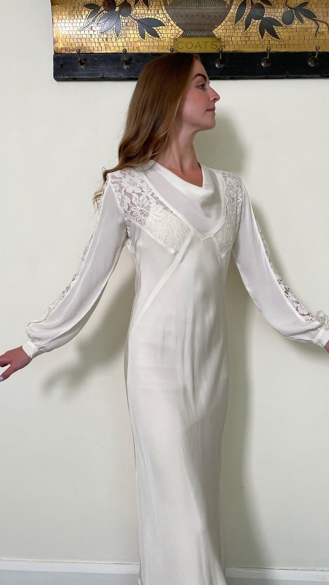 creamy white coloured jersey rayon fabric long sleeve floor length wedding dress. cowl neck and the sleeves and bodice panels are inset with white machine lace which has a floral design. The sleeves have a lovely shape and billow outwards at the wrist when worn